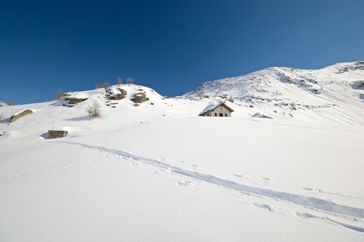 Little chapel high in the mountains with powder snow and back country ski tracks near Gran Paradiso National Park