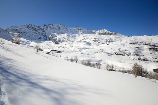 Candid off piste ski slope in scenic background of high mountain peaks, Gran Paradiso National Park, italian Alps