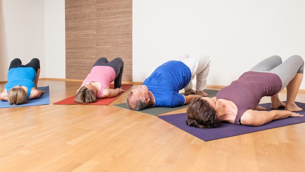 An image of some people doing yoga exercises - Setu Bandha Sarvangasana