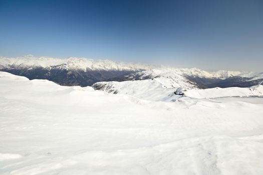 Ski resort and snowy slope in scenic background of high mountain peak