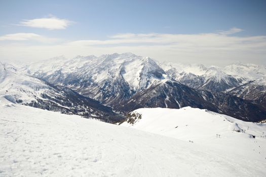 Ski resort and snowy slope in scenic background of high mountain peak