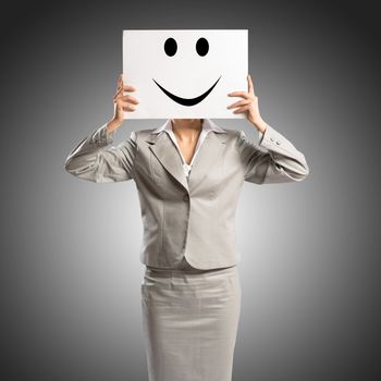 business woman holding a poster with a painted face on it instead of a face, the concept of duplicity in business