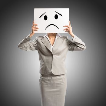 business woman holding a poster with a painted face on it instead of a face, the concept of duplicity in business