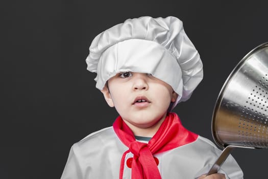 Childhood, Little boy preparing healthy food on kitchen over grey background, cook hat