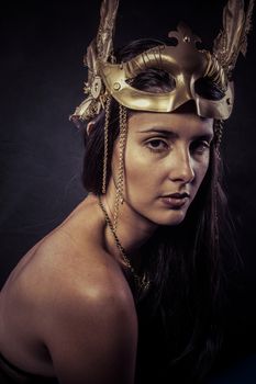 Valkyrie, Golden statue concept. Arty portrait of model with golden mask and shiny lashes. Perfect sporty body. Long hair. Profile. Female