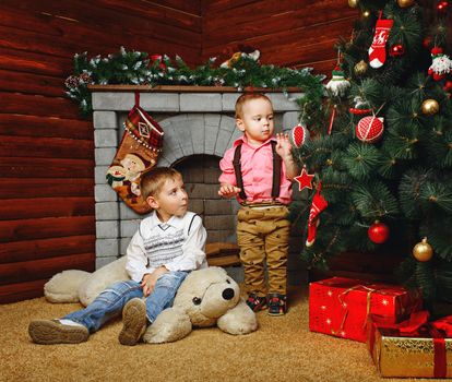 Two brothers near decorated Christmas tree pending holiday
