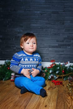 Little boy sitting on the floor surrounded by Christmas decorations