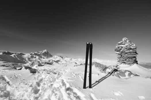 Pair of back country ski on the summit cairn with superb view of the italian alpine arc