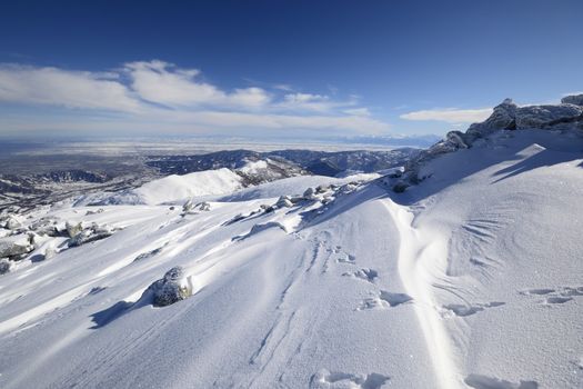 Candid off-piste ski slope in scenic background of mountain peaks, valleys and plain. Piedmont, Italian Alps