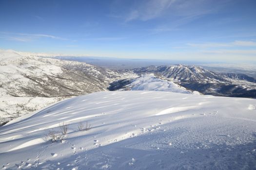 Candid off-piste ski slope in scenic background of mountain peaks, valleys and plain. Piedmont, Italian Alps