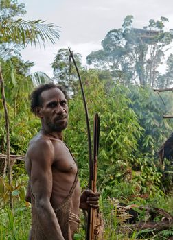  ONNI VILLAGE, NEW GUINEA, INDONESIA - JUNY 24: The Portrait Leon - Korowai man with bow and strikes on the natural green forest background. On June 24, 2012 in Onni Village, New Guinea, Indonesia 