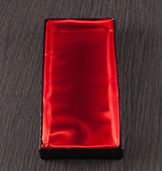 Red satin empty box over wooden background