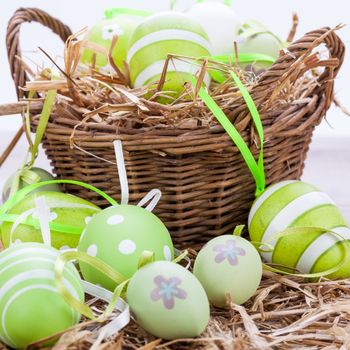 Collection of four hand decorated colourful green Easter eggs with different patterns displayed in straw, close up view