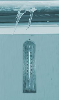 Frozen thermometer over a wall, under ice and snow