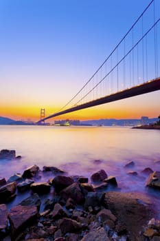 Bridge at coast with sea stones in sunset