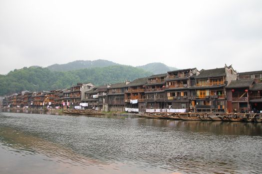 FENGHUANG - MAY 12: Wooden boat and wooden houses at tuojiang river in fenghuang ancient town on May 12, 2011 in Fenghuang, China.