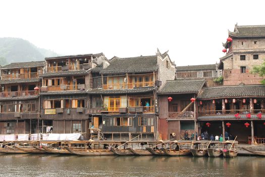 FENGHUANG - MAY 12: Wooden boat and wooden houses at tuojiang river in fenghuang ancient town on May 12, 2011 in Fenghuang, China.