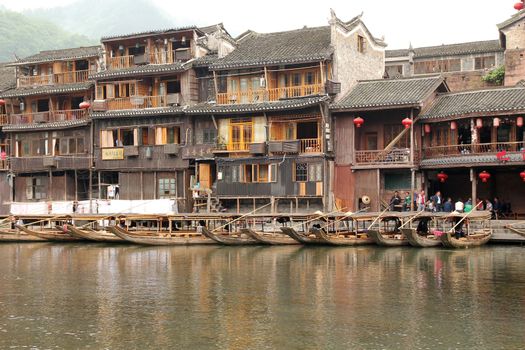 FENGHUANG - MAY 12: Wooden boat and wooden houses at tuojiang river in fenghuang ancient town on May 12, 2011 in Fenghuang, China.