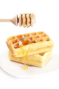 Belgian waffles on a plate, stick for honey and honey isolated on white