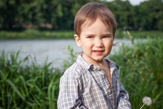 Child with dandelion outdoor near a river