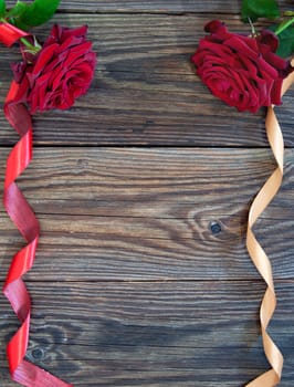 Red roses with decorative ribbon over a wooden background 