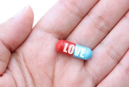 Hand holding a capsule labeled love 