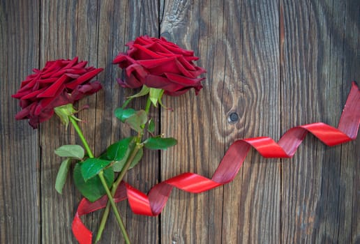 Red roses with decorative ribbon over old wood 