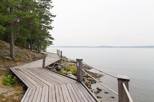 Scandinavian summer. Rocky lakeshore with wooden pathway.