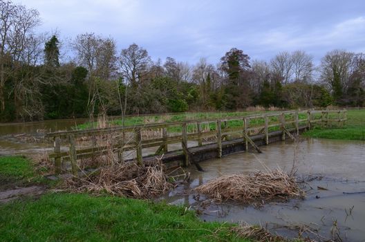 A rustic wooden footbridge crossing a swollen river.