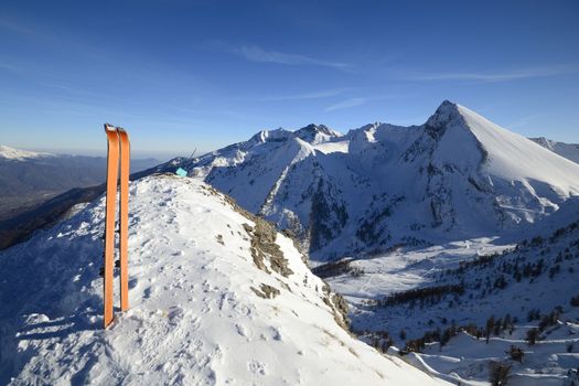 Wide angle view of a pair of back country ski on the top of the mountain in a clear bright day and scenic winter background