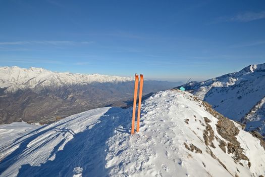 Wide angle view of a pair of back country ski on the top of the mountain in a clear bright day and scenic winter background