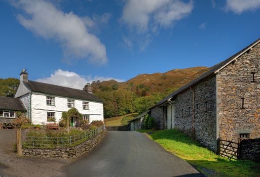 White-washed farmhouse and barns near Loughrigg Tarn, Cumbria, England.