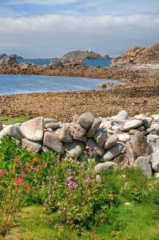 Looking over a dry-stone wall towards Round Island Lighthouse, St Martin���s, Isles of Scilly, Cornwall, England.