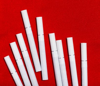 scattered white cigarettes on red background. close-up