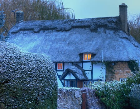 Black and white, timber-framed thatched cottage in winter, Mickleton near Chipping Campden, Gloucestershire, England.