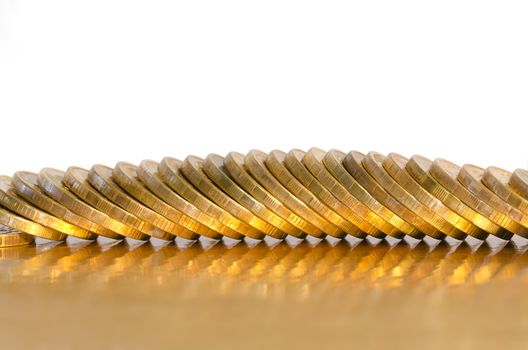 A number of coins, located on the edge of a Golden surface, isolated on white background