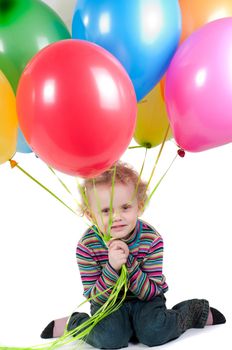 Little girl with multicolored air balloons sitting on the floor