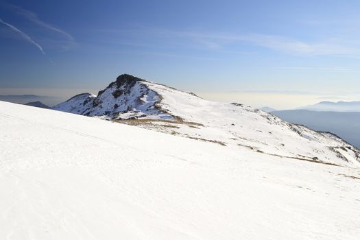 Candid off-piste ski slope in scenic background of mountain peaks, valleys and plain. Piedmont, Italian Alps