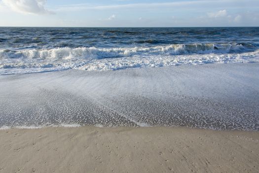 Beach at the North Sea on the Island Sylt in Germany with waves and blue sky
