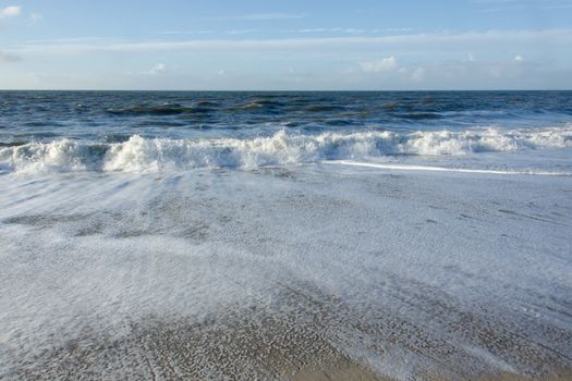 Beach at the North Sea on the Island Sylt in Germany with waves and blue sky