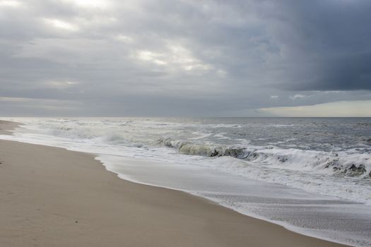 Beach with waves and gray rain clouds on a windy day