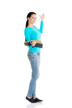 Happy young woman (student or teacher) with book in hand showing on copy space. Isolated on white.