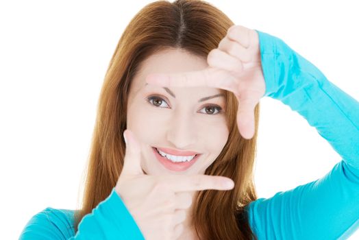 Smiling woman wearing blue blouse is showing frame by hands. Happy girl with face in frame of palms. Isolated on white background.