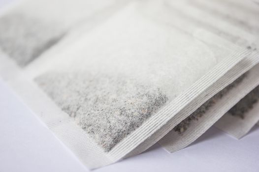 Multiple tea bags lying around on a white background.