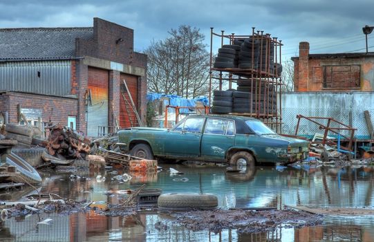 Scrapyard showing flood water and old car, Worcestershire, England.