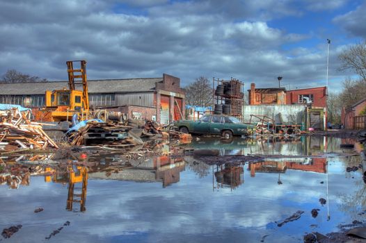 Scrapyard showing flood water and old car, Worcestershire, England.