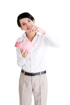 Happy businesswoman putting an euro coin into a piggy bank isolated on white background