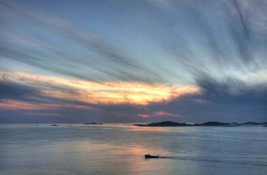 Lone boat passing Samson island at sunset from St Mary���s, Isles of Scilly, Cornwall, England.