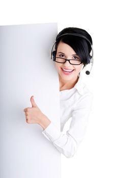 Pretty young call center worker wearing a headset and holding blank sign board