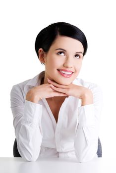 Young beautiful happy businesswoman behind the desk looking up on copy space, isolated